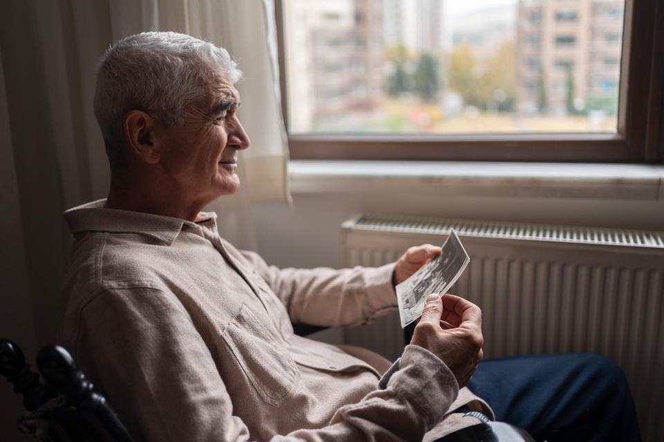 Senior Man Looking At An Old Photo At Home