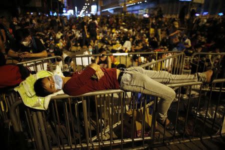 A pro-democracy protester sleeps over a barricade at the Mongkok shopping district of Hong Kong October 20, 2014. REUTERS/Carlos Barria
