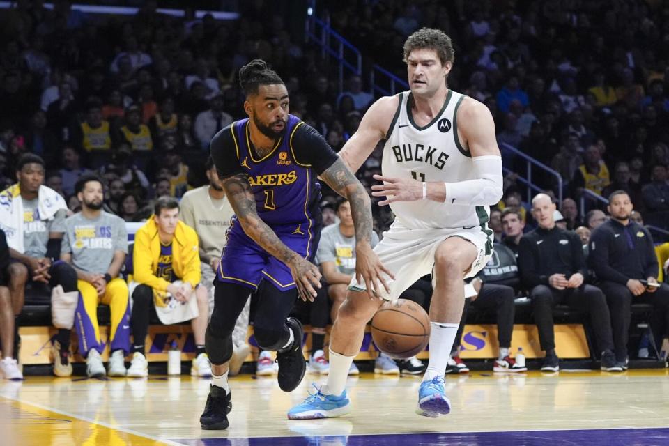 El guardia de los Lakers, D'Angelo Russell, izquierda, desliza un pase alrededor del centro de los Bucks, Brook López, durante la primera mitad el viernes por la noche.