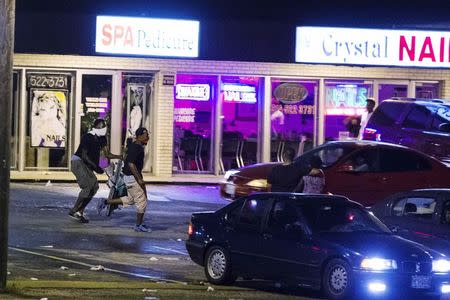 Masked individuals carry items out of a store, during on-going demonstrations to protest against the shooting of Michael Brown, in Ferguson, Missouri, August 16, 2014. REUTERS/Lucas Jackson