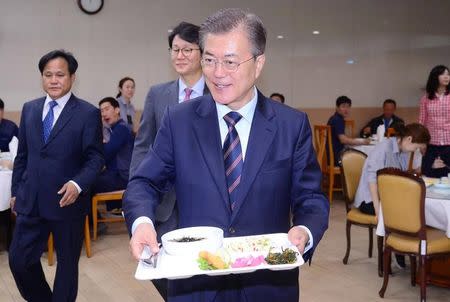 South Korean President Moon Jae-in carries a food tray as he has lunch with technical staff of the Presidential Blue House at an employee cafeteria of the Presidential Blue House in Seoul, South Korea May 12, 2017. Yonhap via REUTERS
