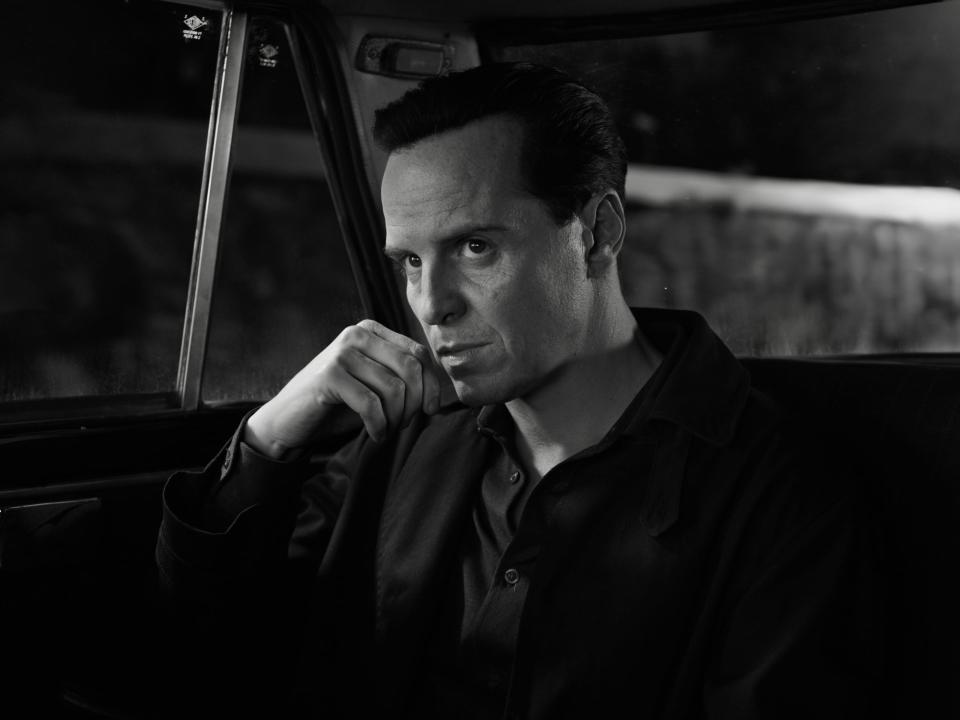 andrew scott, seen in black and white, sitting in the back of a car looking intent