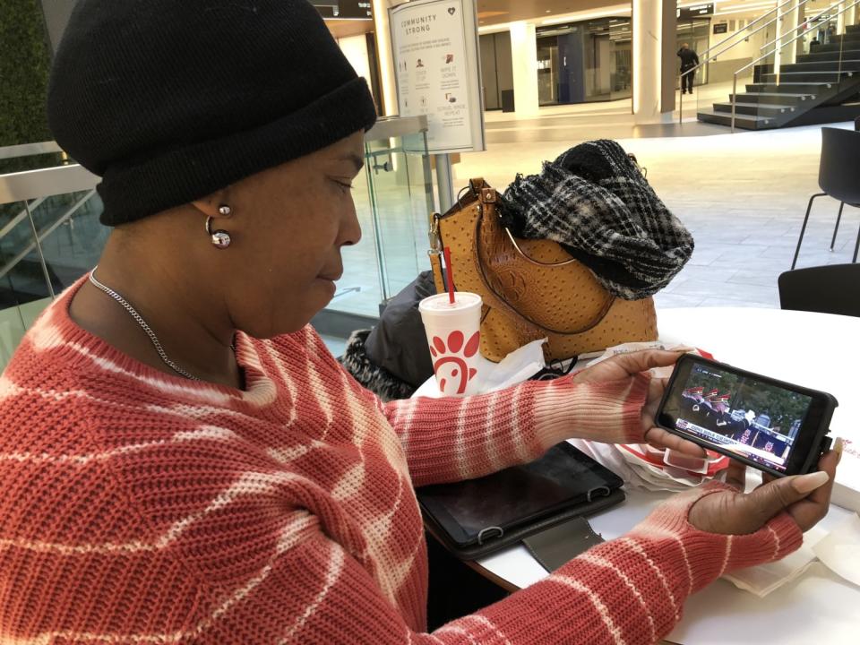 Keonice Fortune, a 46-year-old coffeehouse manager, looks at cellphone images of President Biden's ceremony.