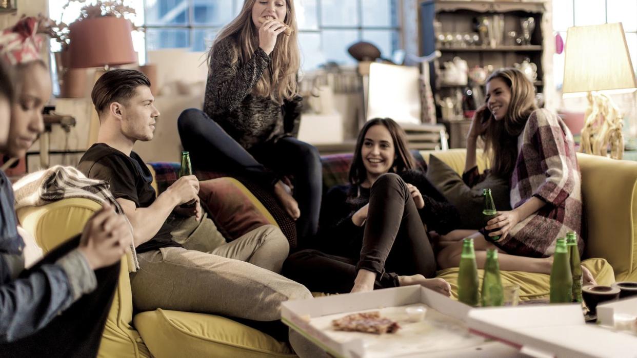 friends sitting on couch eating pizza hanging out