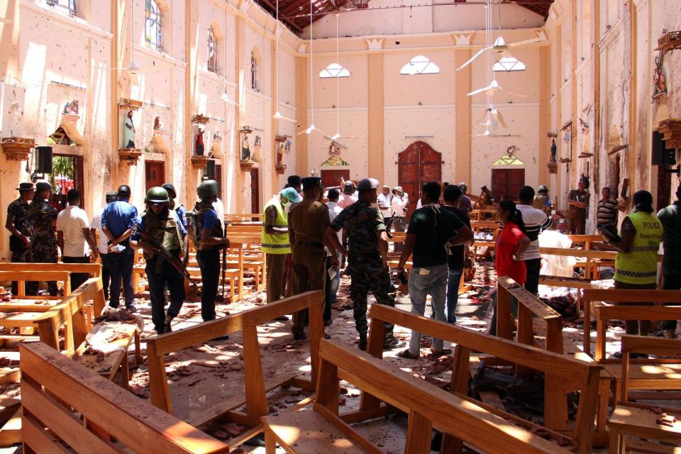 Sri Lankan security personnel walk through debris following an explosion in St Sebastian's Church in Negombo, north of the capital Colombo (AFP/Getty Images)