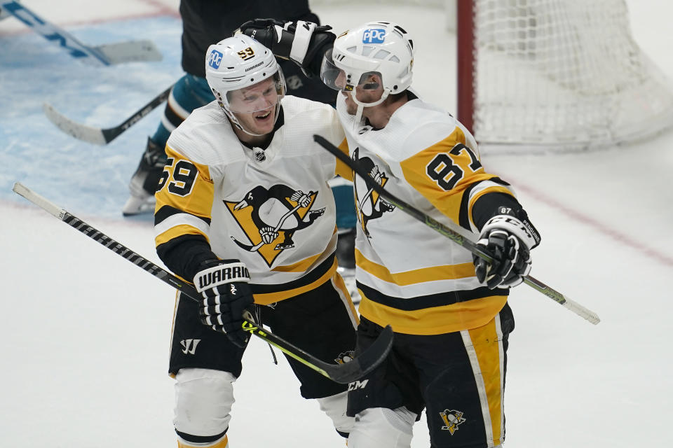 Pittsburgh Penguins left wing Jake Guentzel, left, is congratulated by center Sidney Crosby (87) after scoring during overtime of an NHL hockey game against the San Jose Sharks in San Jose, Calif., Saturday, Jan. 15, 2022. The Penguins won 2-1. (AP Photo/Jeff Chiu)