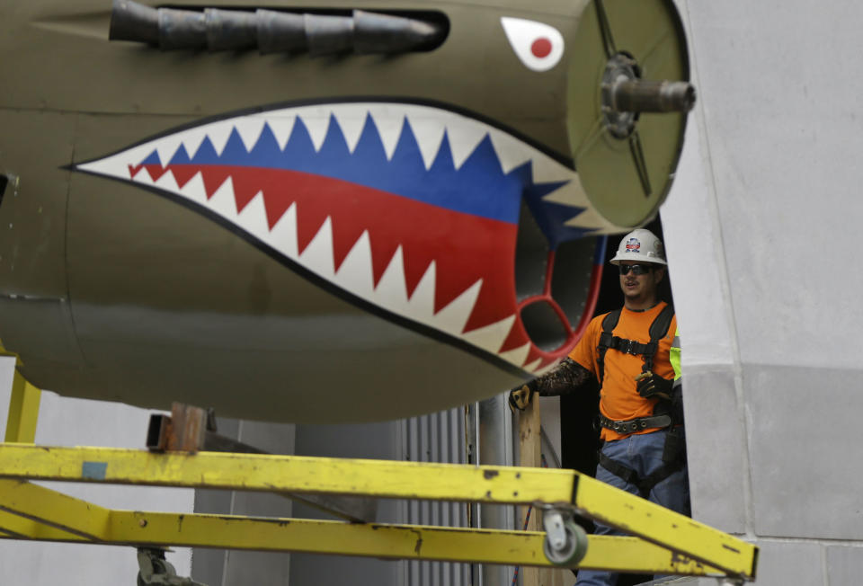 A restored P-40 Curtiss Warhawk fighter plane, one of only 32 known remaining in the world, is hoisted by crane to the second floor for permanent display at the National World War II Museum in New Orleans, Monday, Feb. 3, 2014. The plane, painted in the scheme of the famed Flying Tigers, will be displayed in the museum’s new pavilion, Campaigns of Courage: European and Pacific Theaters. (AP Photo/Gerald Herbert)