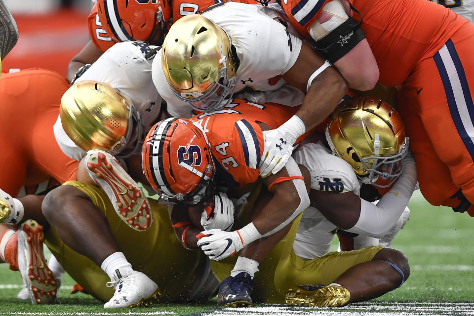 Syracuse running back Sean Tucker (34) is tackled by Notre Dame defenders during the first half of an NCAA college football game in Syracuse, N.Y., Saturday, Oct. 29, 2022. (AP Photo/Adrian Kraus)