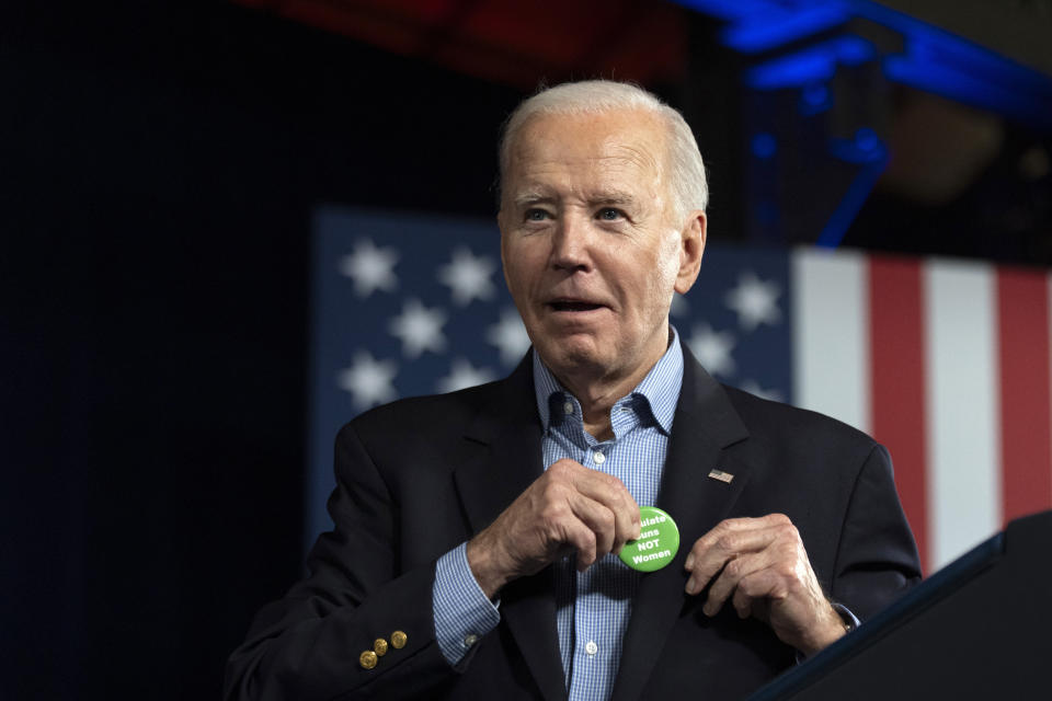 President Joe Biden puts on a button that was thrown to him from the crowd that says "Regulate Guns NOT Women" as he speaks at a campaign rally Saturday, March 9, 2024, at Pullman Yards in Atlanta. (AP Photo/Manuel Balce Ceneta)