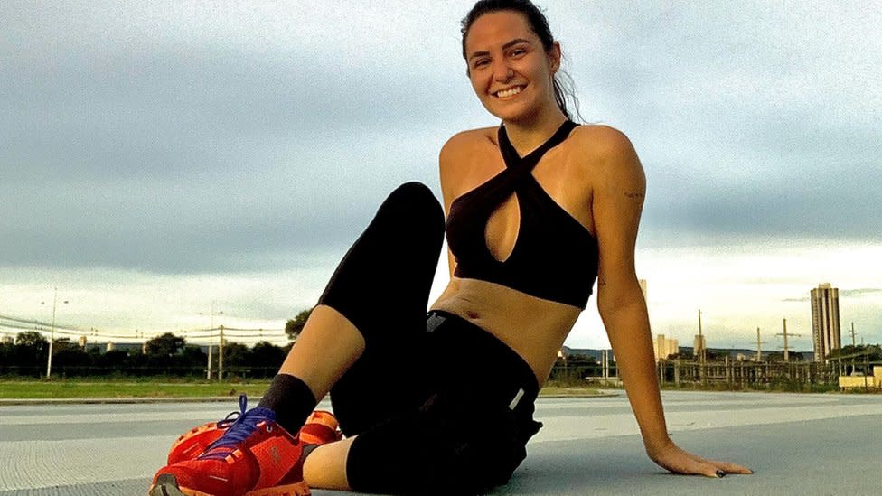 Lísia con ropa deportiva, sentada en el piso y sonriendo