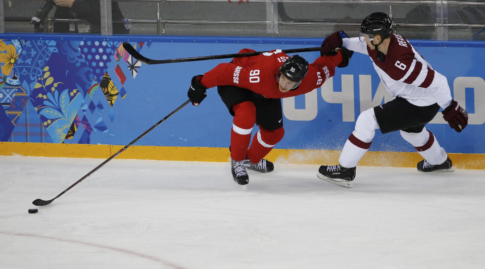 Switzerland defenseman Roman Josi and Latvia defenseman Arvids Rekis battle for control of the puck during the first round of the 2014 Winter Olympics men's ice hockey game at Shayba Arena, Wednesday, Feb. 12, 2014, in Sochi, Russia. (AP Photo/Petr David Josek)