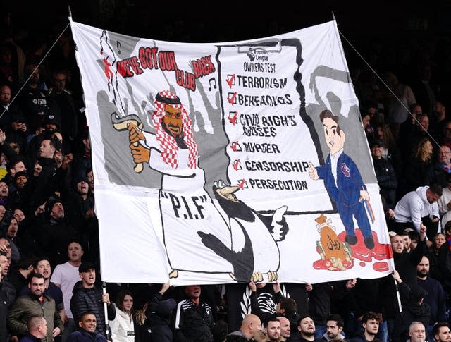 Crystal Palace fans hold up a banner criticising the new ownership of Newcastle