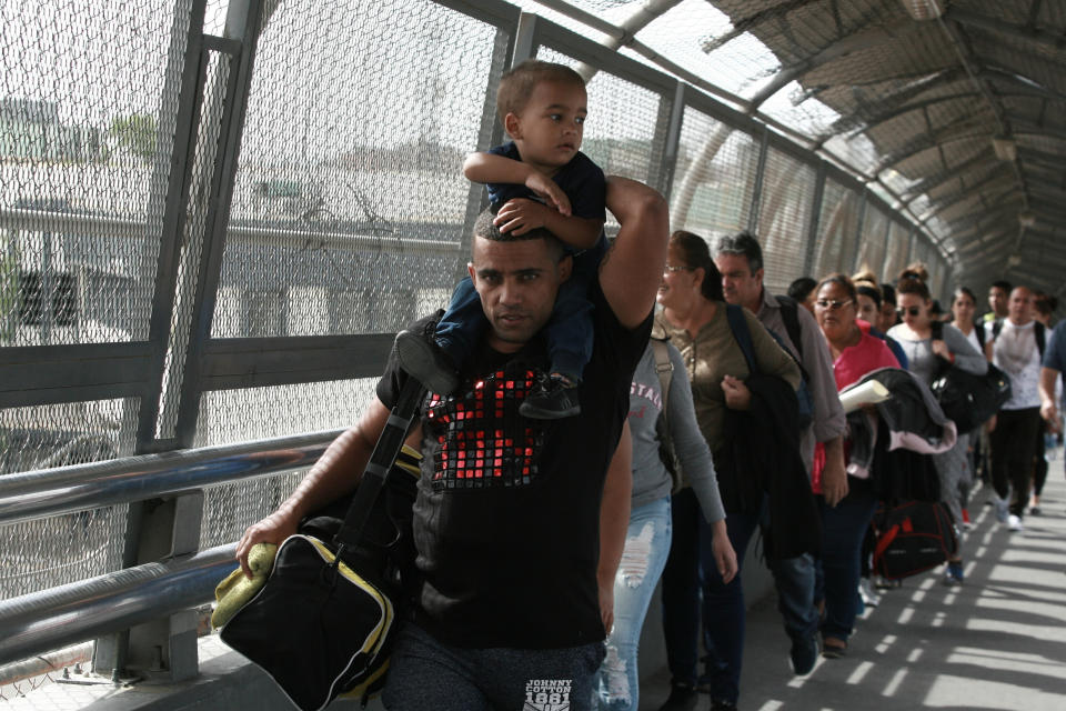 In this April 29, 2019, photo, Cuban migrants are escorted by Mexican immigration officials in Ciudad Juarez, Mexico, as they cross the Paso del Norte International bridge to be processed as asylum seekers on the U.S. side of the border. Burgeoning numbers of Cubans are trying to get into the U.S. by way of the Mexican border, creating a big backlog of people waiting on the Mexican side for months for their chance to apply for asylum. (AP Photo/Christian Torres)