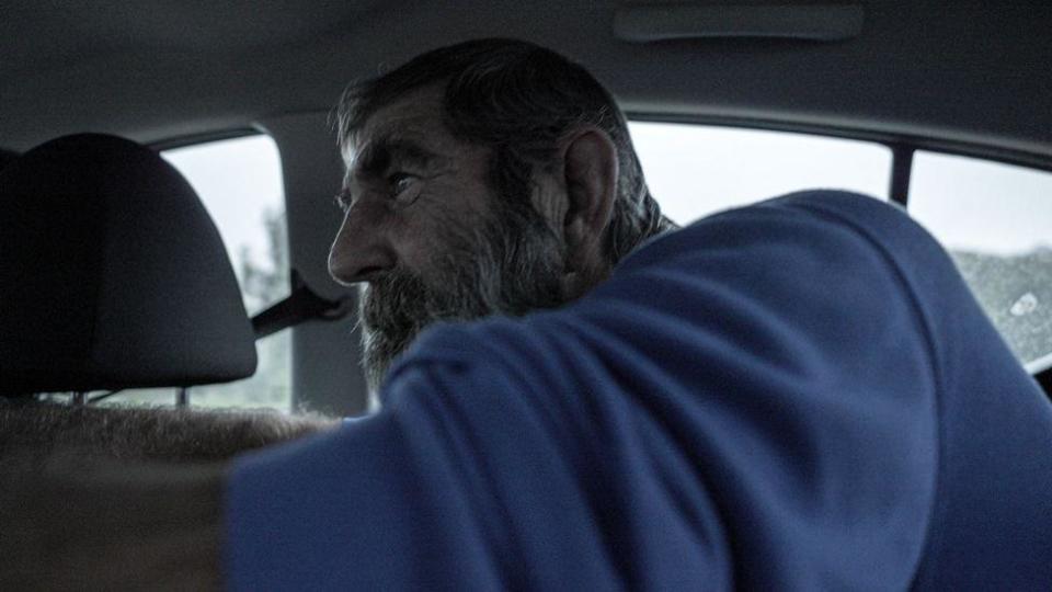 Louis van Schoor in the back of a car, pointing out locations