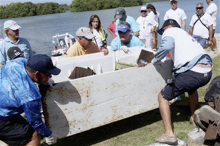 U.S. artist and conservationist Guy Harvey, (near 2nd R, blue visor), helps collect garbage as he leads a group of volunteers along the San Juan estuary system for the second "mega cleanup" of trash from the waterway, in San Juan October 26, 2013. REUTERS/Alvin Baez