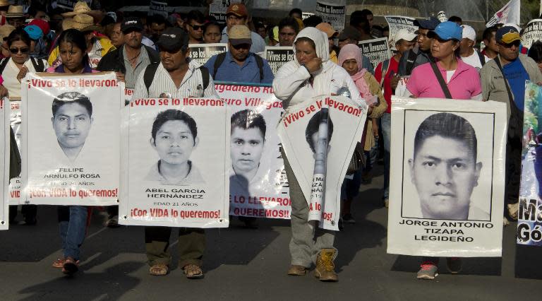 Relatives of the 43 missing students from Ayotzinapa hold their portraits during a march commemorating five months after their disappearance, February 26, 2015, in Mexico City