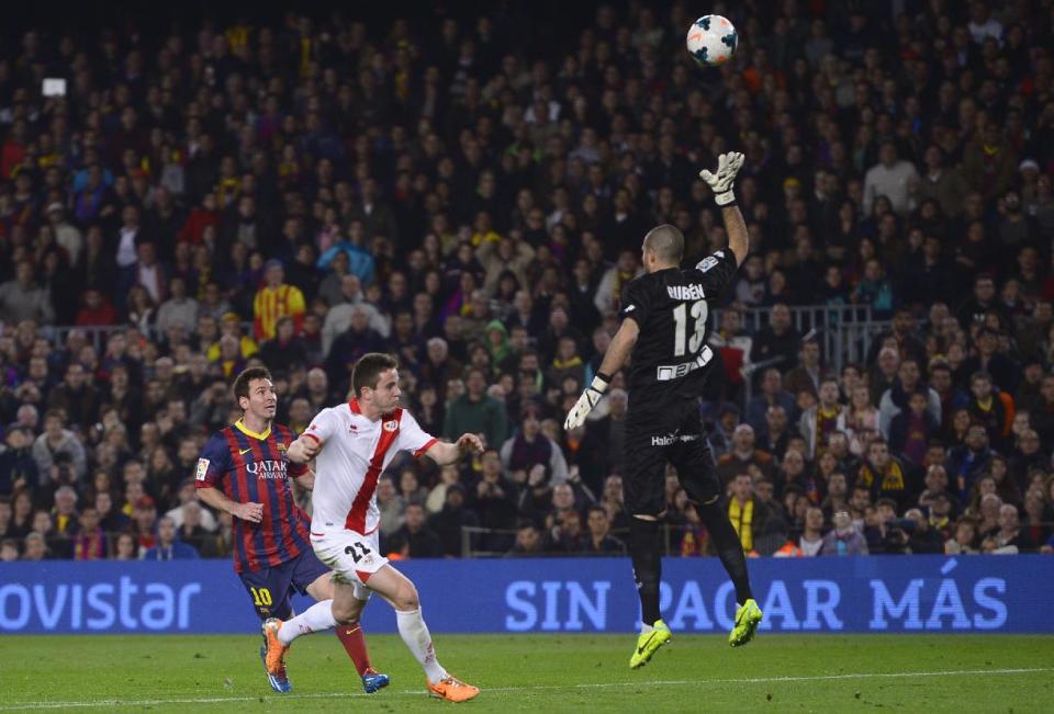 FC Barcelona's Lionel Messi, from Argentina, left, scores against Rayo Vallecano's goalkeeper Ruben Martinez, right, during a Spanish La Liga soccer match at the Camp Nou stadium in Barcelona, Spain, Saturday, Feb. 15, 2014. (AP Photo/Manu Fernandez)