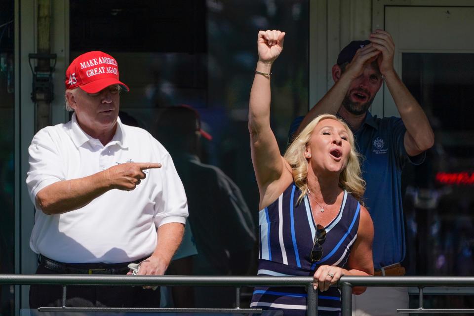 Former President Donald Trump, left, acknowledges the crowd with U.S. Rep. Marjorie Taylor Greene while they look over the 16th tee during the second round of the Bedminster Invitational LIV Golf tournament.