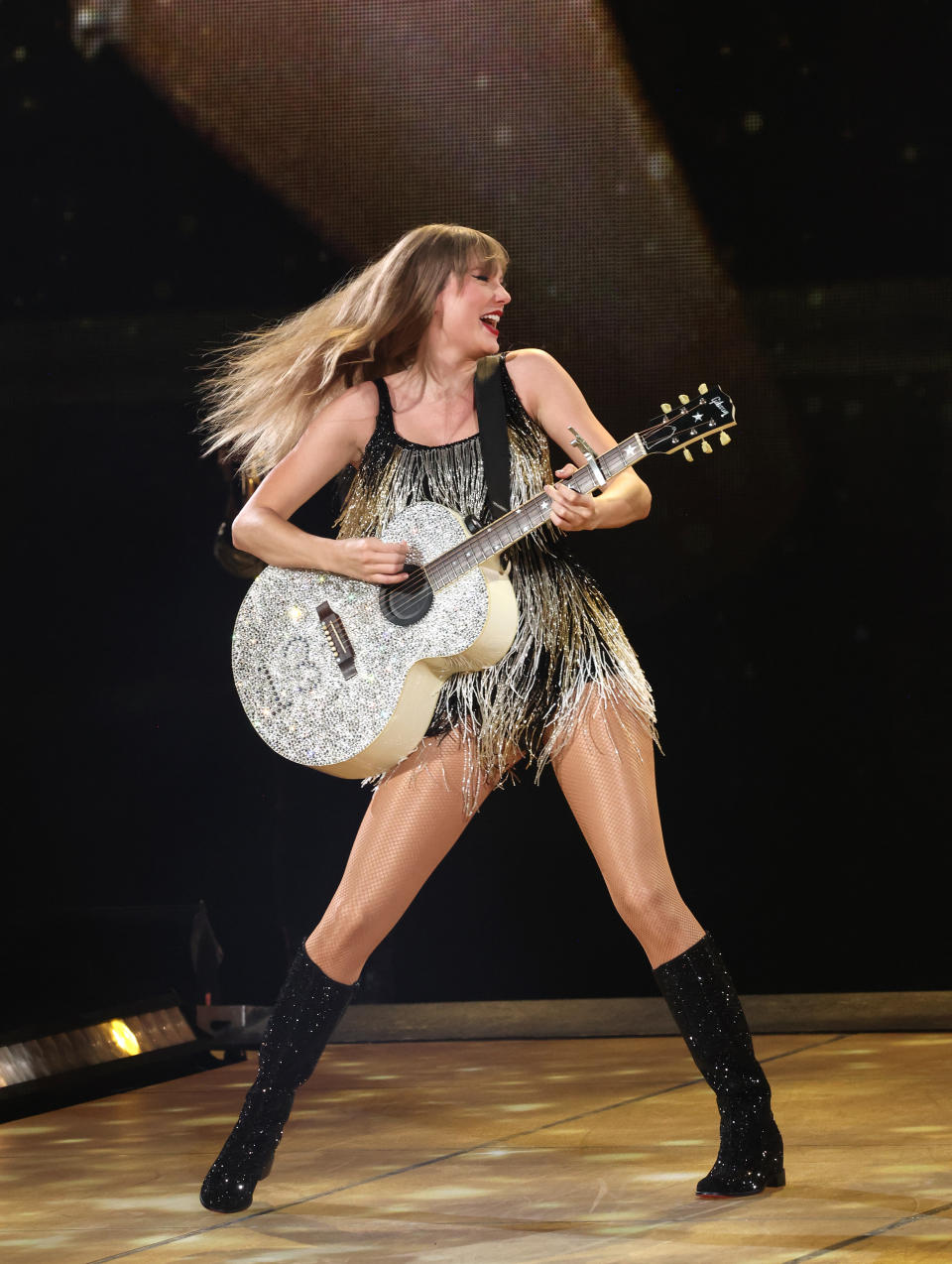 Taylor Swift playing guitar onstage.