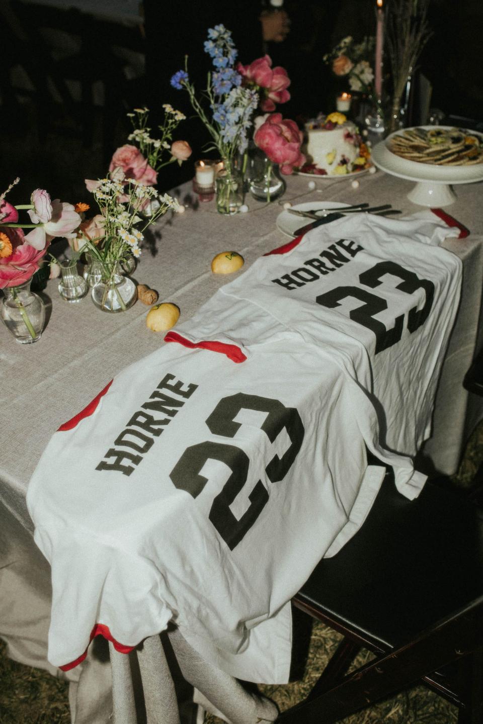 Two jerseys that say "Horne" with 23 on them sit on a table with flower vases.