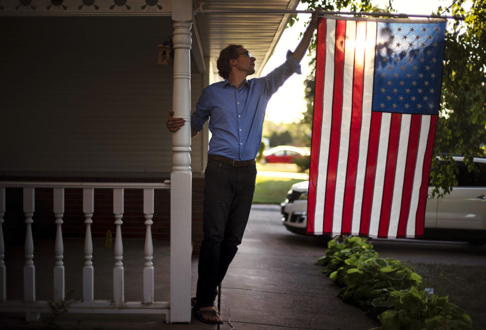 Outagamie County Executive Tom Nelson adjusts the American flag hanging off his front porch in Appleton, Wis., Aug. 18, 2020. By his estimate, the county would have lost a catastrophic 2,000 jobs as collateral damage if the Midwest Paper Group mill closed. Nelson, the workers and their union representation lobbied the bankruptcy court and struck a deal. "If it were not for the fact that the mill was unionized, it would be a trash heap," Nelson said. (AP Photo/David Goldman)