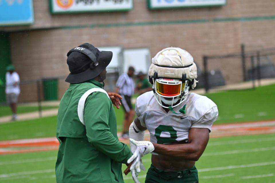 Florida A&M University defensive pass game coordinator and cornerbacks coach James Colzie III (left) shakes hands with defensive back Eric Smith (right) in team’s second preseason scrimmage, Aug. 13, 2022