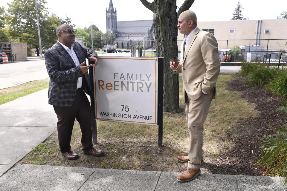 In this Wednesday, Aug. 10, 2022 photo, Fred Hodges, left, and Da'ee McKnight talk outside where they work at Family ReEntry a reentry support group aiming to break cycles of violence, crime and incarceration in Bridgeport, Conn. Hodges and McKnight are former Connecticut inmates who have been paying for cost of their incarceration. (AP Photo/Jessica Hill)