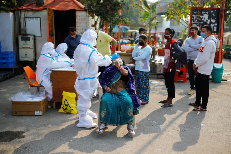 A healthcare worker collects a swab sample from a man in Noida