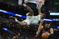 Milwaukee Bucks' Thanasis Antetokounmpo (43) hangs from the rim after dunking over Miami Heat's Max Strus during the second half of an NBA basketball game Saturday, Dec. 4, 2021, in Milwaukee. (AP Photo/Morry Gash)