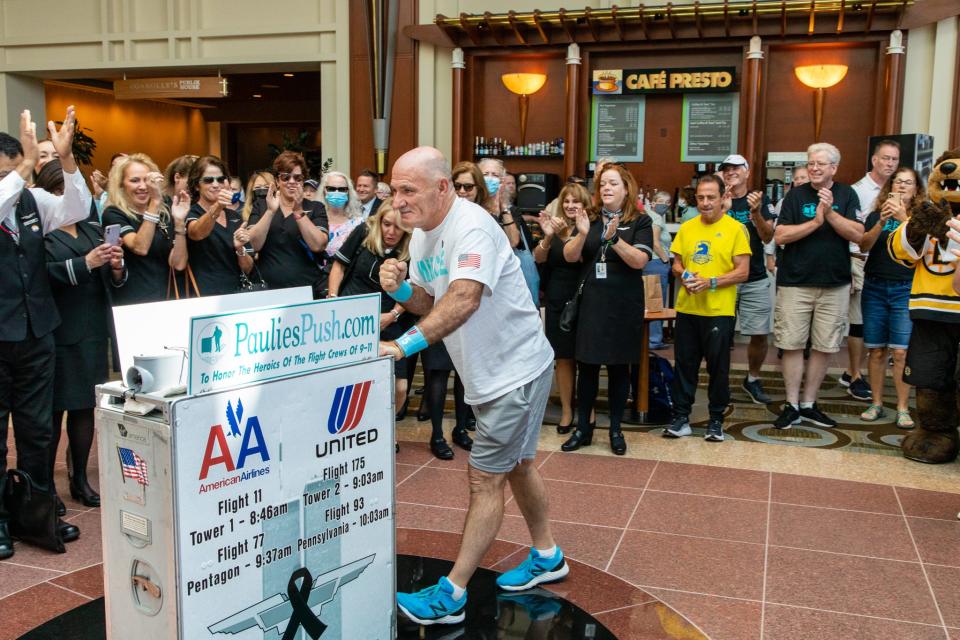 Paulie Veneto, a former United Airlines flight attendant, pushes an airline service cart through the Hilton lobby as he is cheered on by United Airlines flight attendants, friends and family on Saturday, Aug. 21, 2021.