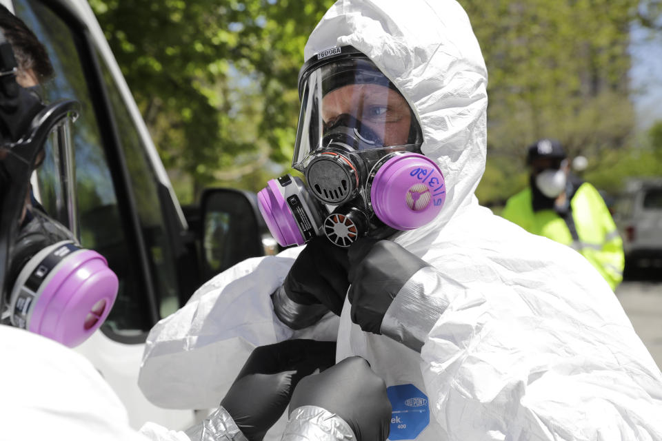 Safety Director Tony Barzelatto gets some help putting on protective gear before disinfecting a floor and common areas in a Co-op City building in the Bronx of New York, Wednesday, May 13, 2020. Regular cleanings occur throughout the common areas of the buildings while the heavy disinfecting occurs in response to specific incidents, in this case reports of two coronavirus cases on the same floor. Within the Bronx, almost no place has been hit as hard as Co-op City. (AP Photo/Seth Wenig)