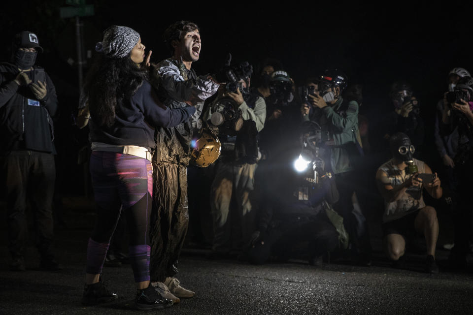 A protester screams at police as they attempt to take control of the streets with Portland protests reaching 100 consecutive nights on Saturday, Sept. 5, 2020, in Portland, Ore. Hundreds of people gathered for rallies and marches against police violence and racial injustice Saturday night in Portland, Oregon, as often violent nightly demonstrations that have happened for 100 days since George Floyd was killed showed no signs of ceasing.(AP Photo/Paula Bronstein)