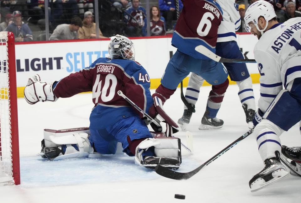 Colorado Avalanche goaltender Alexandar Georgiev, left, looks to block a shot by Toronto Maple Leafs center Zach Aston-Reese during the second period of an NHL hockey game Saturday, Dec. 31, 2022, in Denver. (AP Photo/David Zalubowski)