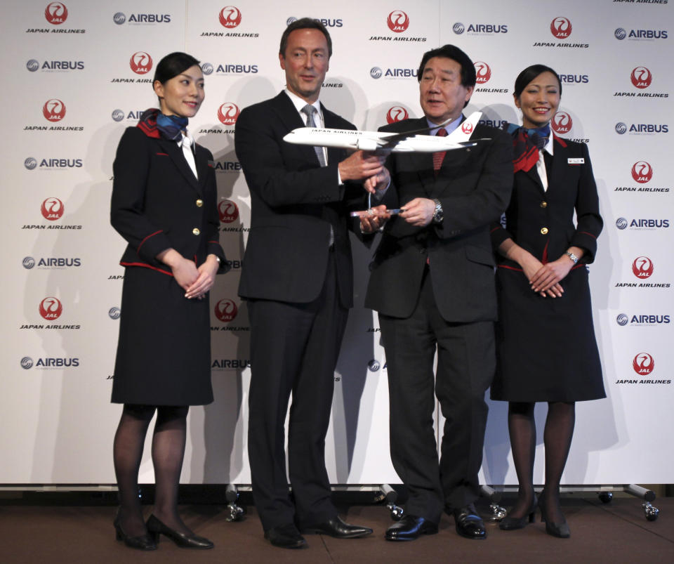 Airbus Japan Chief Executive Fabrice Bregier, center left, and Japan Airlines President Yoshiharu Ueki, center right, hold a model plane of Airbus A350 for photos following their press conference in Tokyo, Monday, Oct. 7, 2013. Japan Airlines is buying its first ever jets from Airbus in a deal with a catalog value of 950 billion yen ($9.5 billion) with a purchase of 31 A350 planes. (AP Photo/Junji Kurokawa)