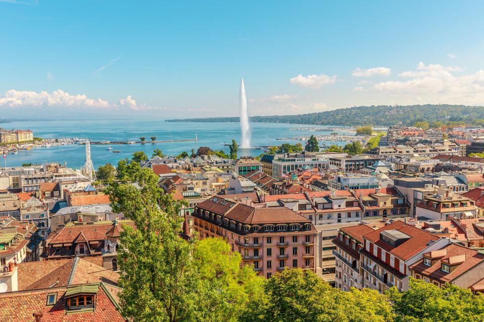 Geneva skyline cityscape, French-Swiss in Switzerland. Aerial view of Jet d'eau fountain, Lake Leman, bay and harbor from the bell tower of Saint-Pierre Cathedral