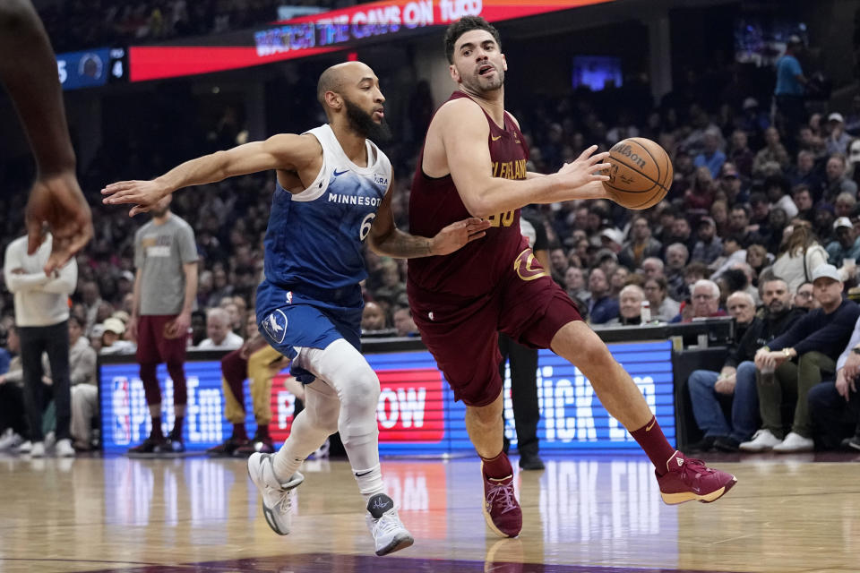 Cleveland Cavaliers forward Georges Niang, right, drives around Minnesota Timberwolves guard Jordan McLaughlin (6) during the first half of an NBA basketball game Friday, March 8, 2024, in Cleveland. (AP Photo/Sue Ogrocki)