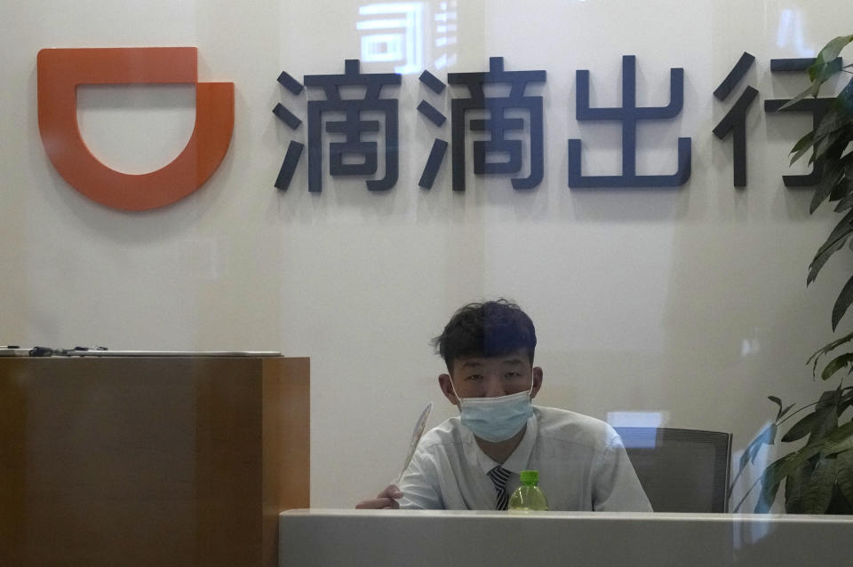 A receptionist looks up near the logo for Didi at an office in Beijing on July 16, 2021. Chinese ride-hailing service Didi Global Inc. said Friday, Dec. 3, 2021 it will pull out of the U.S. stock market and shift its listing to Hong Kong as the ruling Communist Party tightens control over tech industries. (AP Photo/Ng Han Guan)