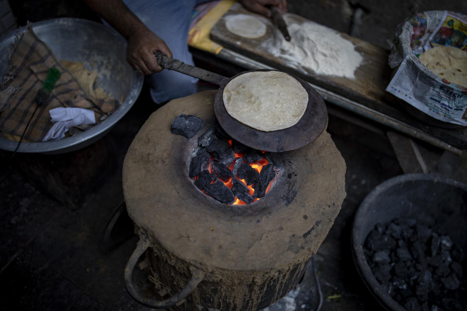 A roadside food stall worker uses coal hearth to make roti or Indian bread in Dhanbad, an eastern Indian city in Jharkhand state, Saturday, Sept. 25, 2021. No country will see energy needs grow faster in coming decades than India, and even under the most optimistic projections part of that demand will have to be met with dirty coal power — a key source of heat-trapping carbon emissions. (AP Photo/Altaf Qadri)