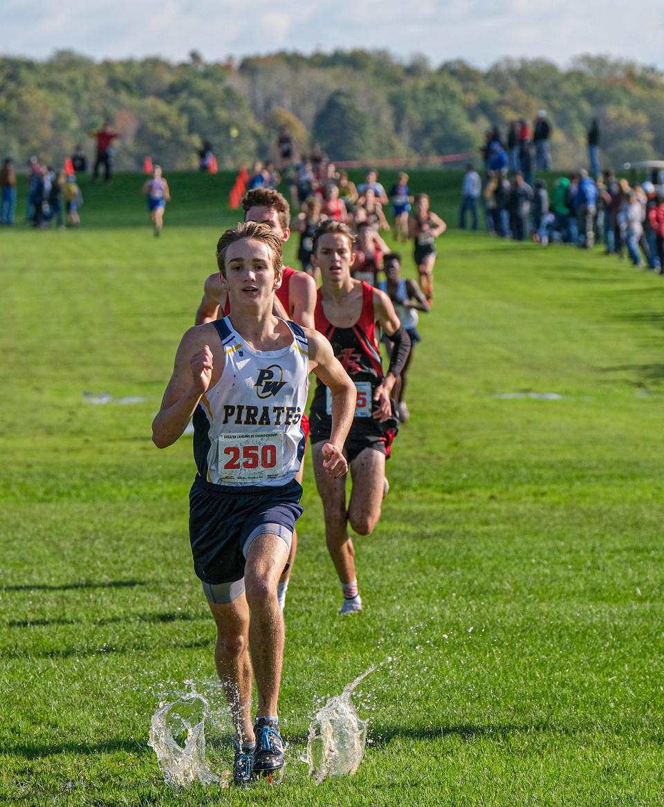 Collin Farmer from Pewamo-Westphalia (250) holds off a long line of competitors at the finish line and takes a second-place in the Greater Lansing Cross Country Championship race Saturday, Oct. 16, 2021.