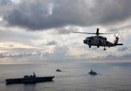 An SH-60K Sea Hawk helicopter flies in front of Japanese helicopter carrier Kaga (L) , Japanese destroyer Inazuma (C) and British frigate HMS Argyle taking part in a joint naval drill in the Indian Ocean, September 26, 2018. Picture taken September 26, 2018. REUTERS/Kim Kyung-Hoon