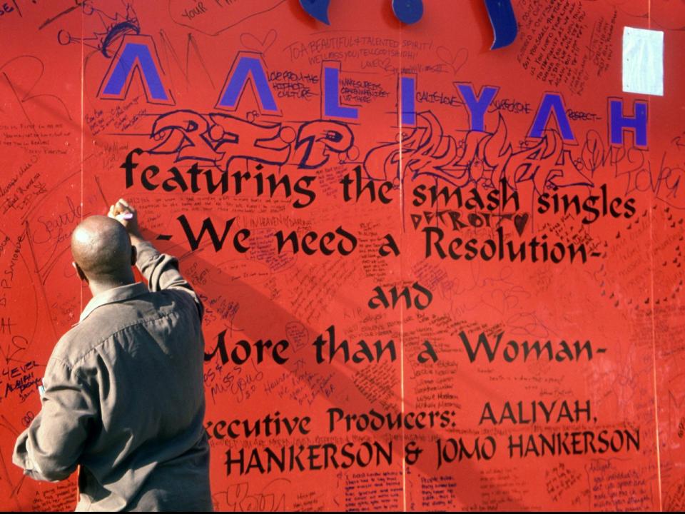 A fan writes on a tribute to Aaliyah on Sunset Boulevard after her funeral, 31 August 2001 (Shutterstock)