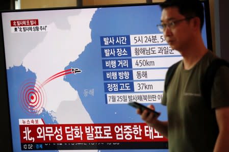 A man walks past a TV broadcasting a news report on North Korea firing two unidentified projectiles, in Seoul