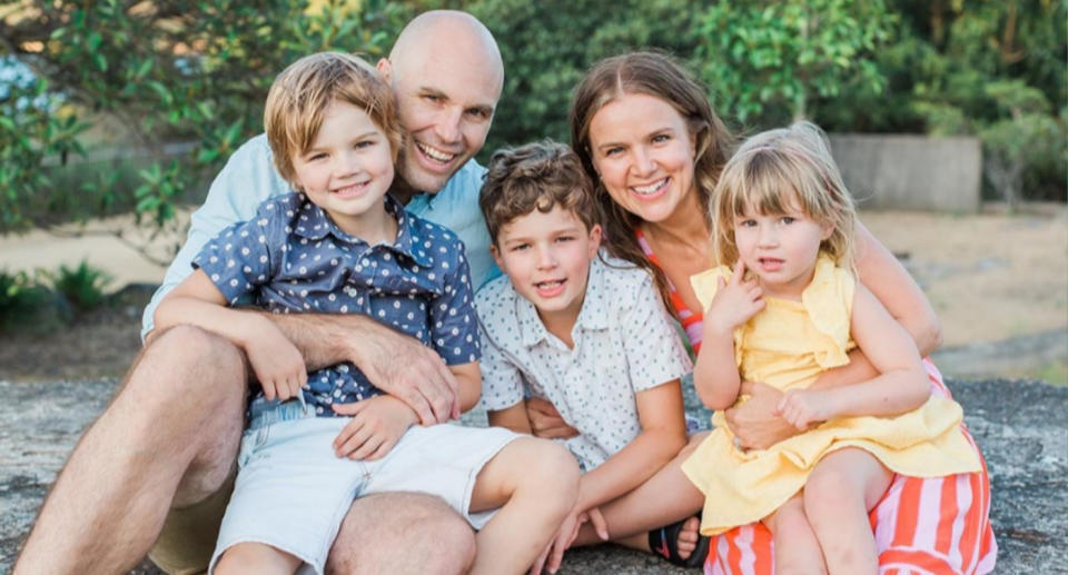 Hugo is pictured sitting on his dad Tom's lap next to his siblings and mum Felicity.