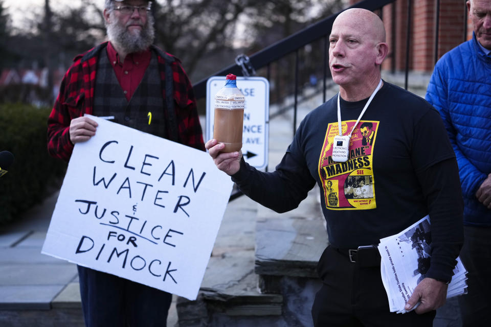 Craig Stevens holds a bottle of brown water as he speaks with members of the media outside the Susquehanna County Courthouse in Montrose, Pa., Tuesday, Nov. 29, 2022. Pennsylvania's most active gas driller has pleaded no contest to criminal environmental charges in a landmark pollution case. Houston-based Coterra Energy Inc. entered its plea Tuesday. (AP Photo/Matt Rourke)