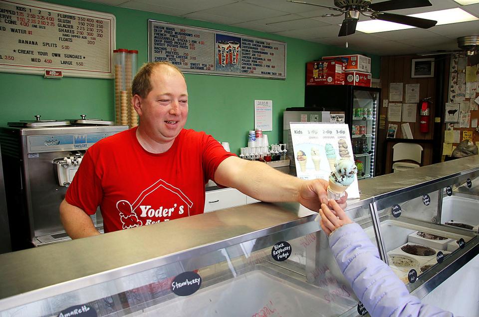 Yoder's Red Barn owner Harley Yoder hands a cone to a young customer on Thursday, April 7, 2022. TOM E. PUSKAR/TIMES-GAZETTE.COM