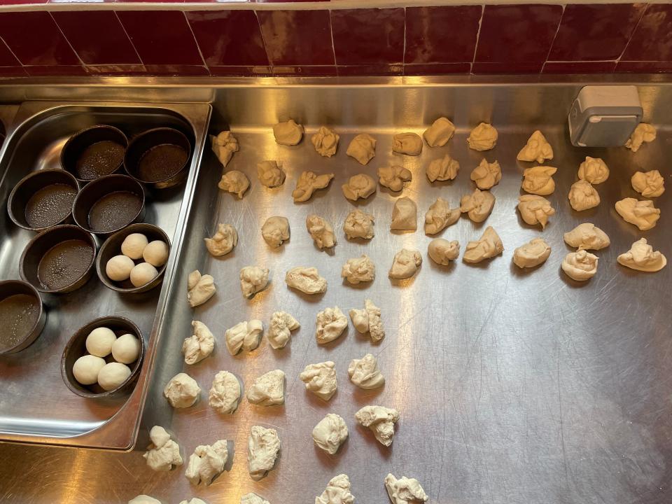 Pieces of bread on a counter and rolls on a tray next to them