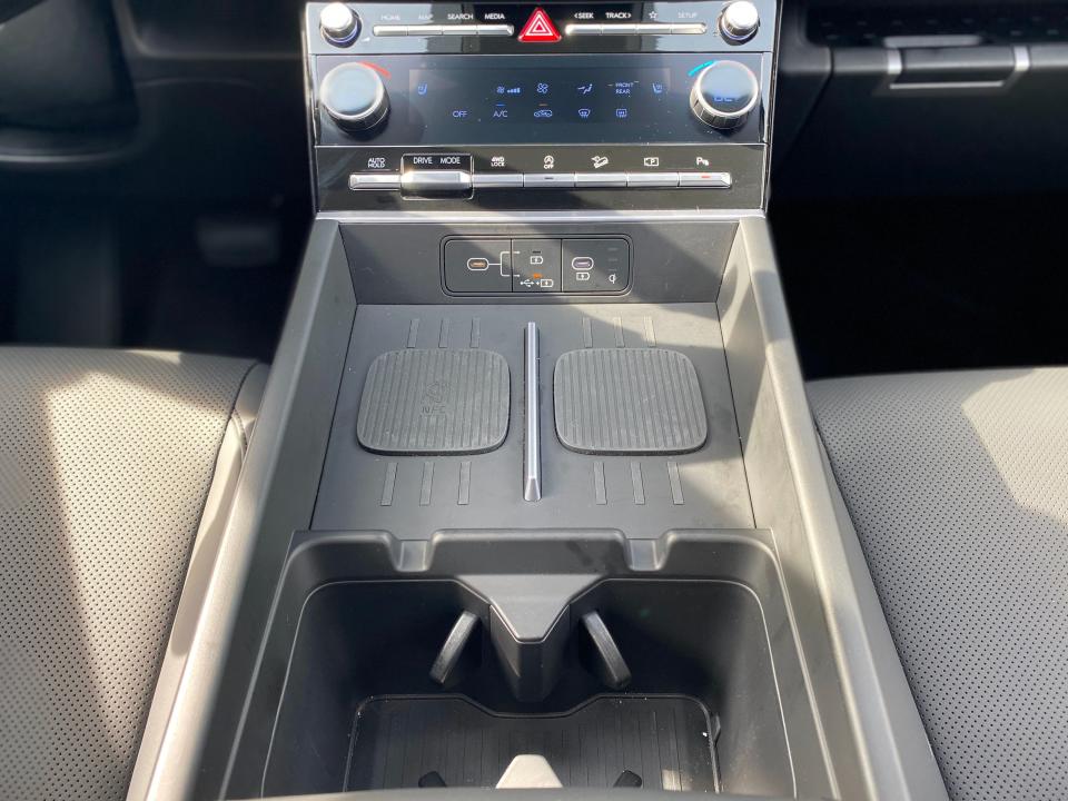 The center console of a 2024 Hyundai Santa Fe XRT SUV with a wireless charger and cup holders.