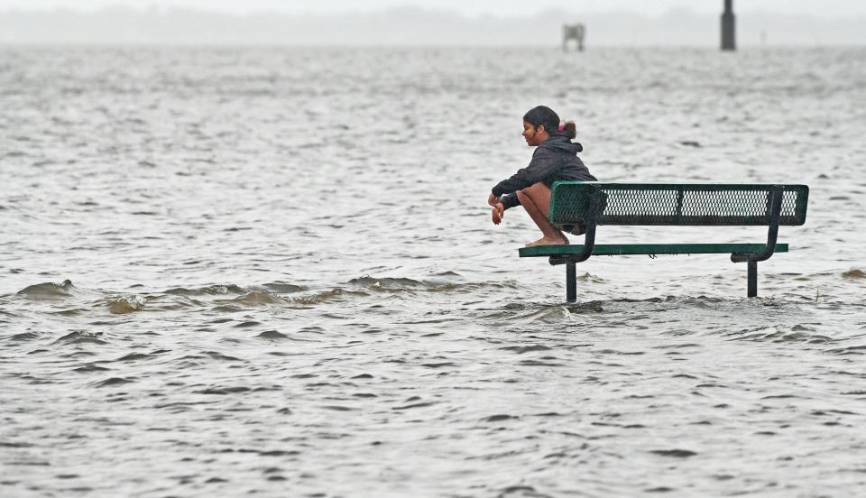 Trinity Moore sits at a park bench at the flooded Port St. John Boat Ramp on Thursday morning.