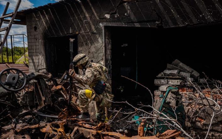 A soldier of the Kraken Ukrainian special forces unit walks past wreckage in the village of Rus'ka Lozova, north of Kharkiv - DIMITAR DILKOFF/AFP