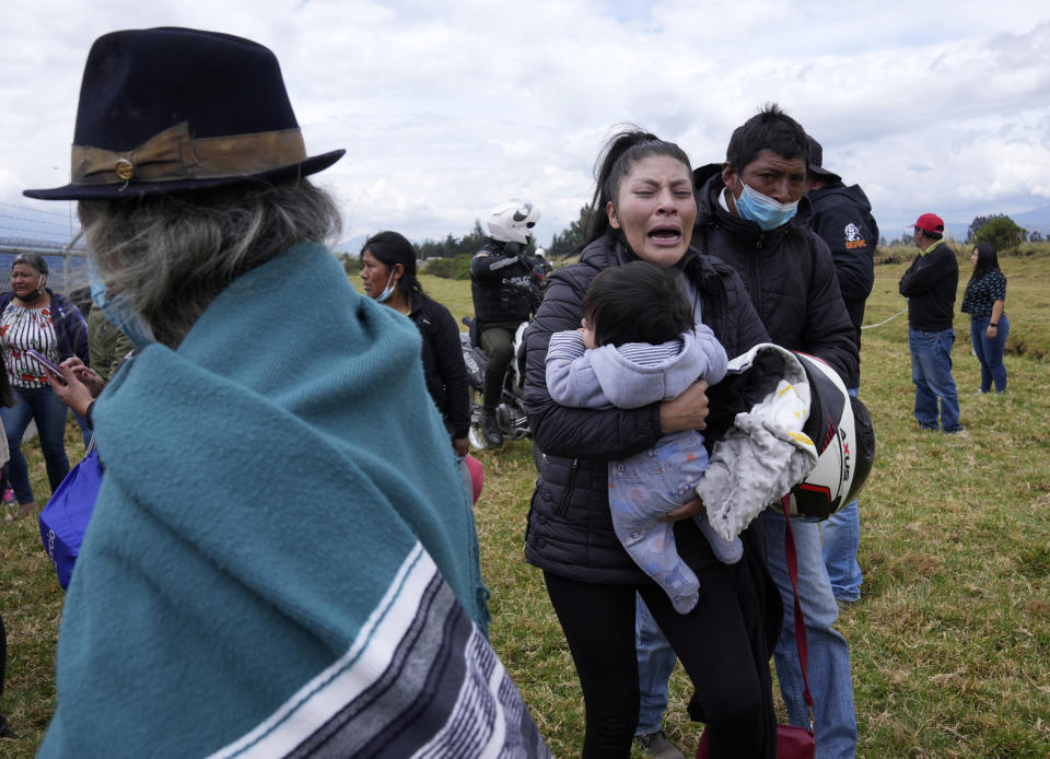 A woman cries holding her child as she waits for news of her loved one held inside Latacunga jail after a deadly riot in Latacunga, Ecuador, Tuesday, Oct. 4, 2022. A clash between inmates armed with guns and knives inside the prison has left at least 15 people dead and 20 injured. (AP Photo/Dolores Ochoa)